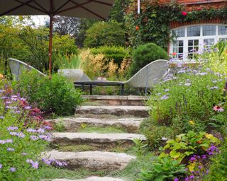 mixed planting on sloped herbaceous beds spilling over onto stone steps in a design by Ann-Marie Powell Gardens