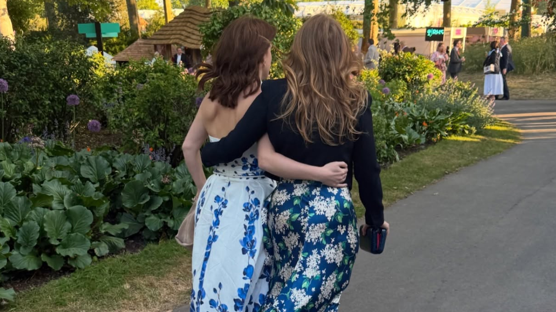 Princess Beatrice and Princess Eugenie walking with their arms around each other at the Chelsea Flower Show