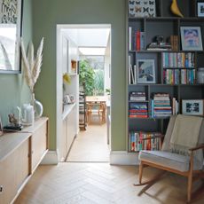 Library area with green walls, bookshelves and a rocking chair