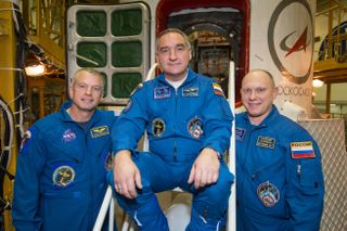 In the Integration Facility at the Baikonur Cosmodrome in Kazakhstan, NASA astronaut Steve Swanson (left) and Alexander Skvortsov (center) and Oleg Artemyev of Roscosmos pose for pictures in front of their Soyuz TMA-12M spacecraft March 21, 2014 ahead of a March 25 launch.