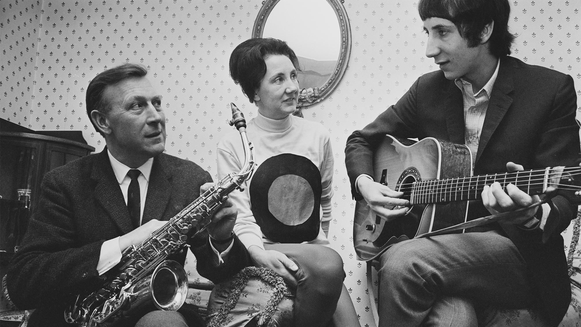 Pete Townshend of The Who pictured playing an acoustic guitar with his father Cliff Townshend (1916-1986), saxophone player with the Squadronaires, and mother Betty at home in London on 30th March 1966.
