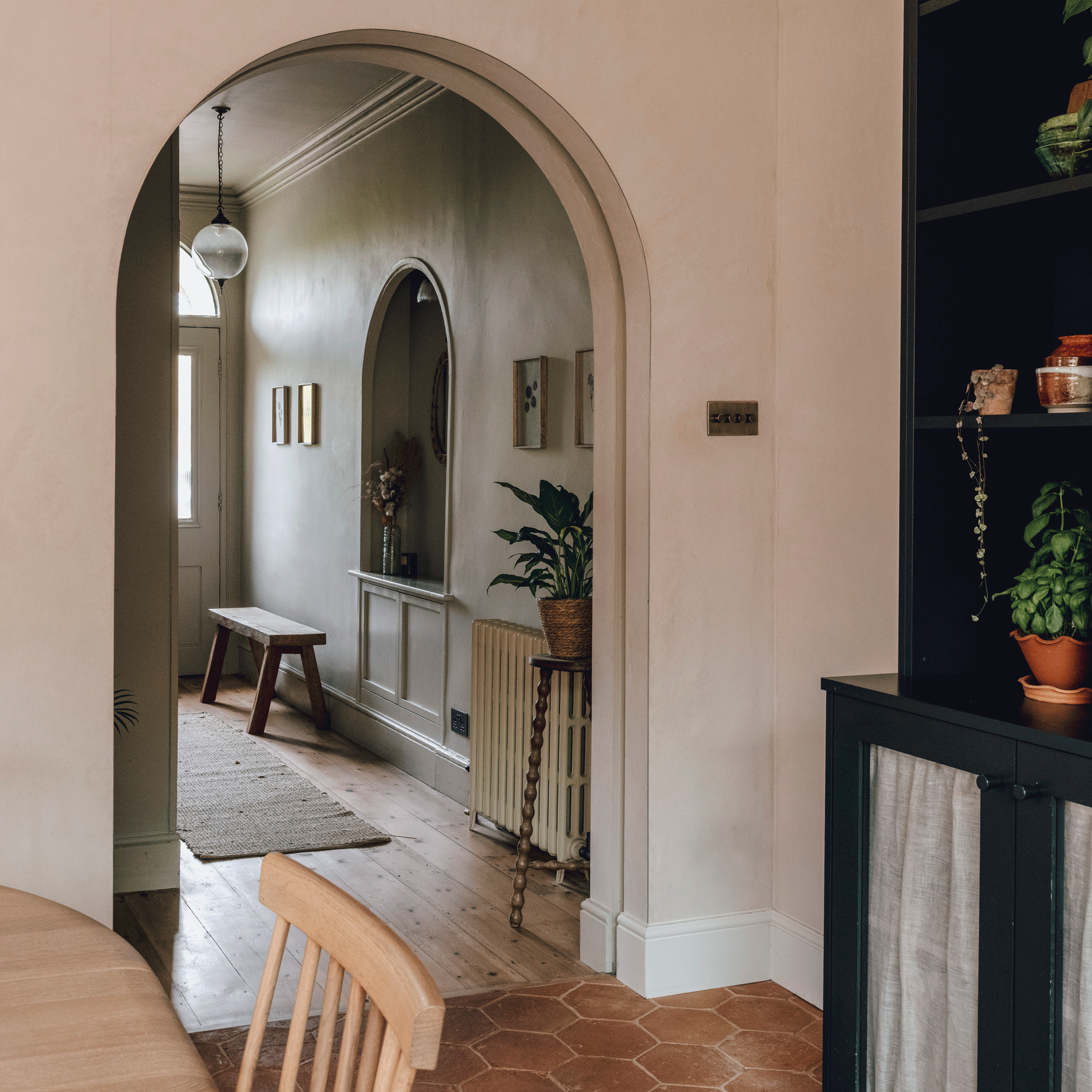 view from a dining area with a dining table and chairs into a hallway via an arched entrance