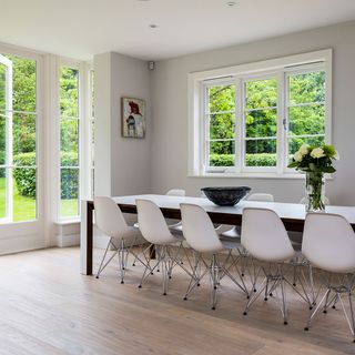 dining area with wooden floor and white wall and white chairs with table
