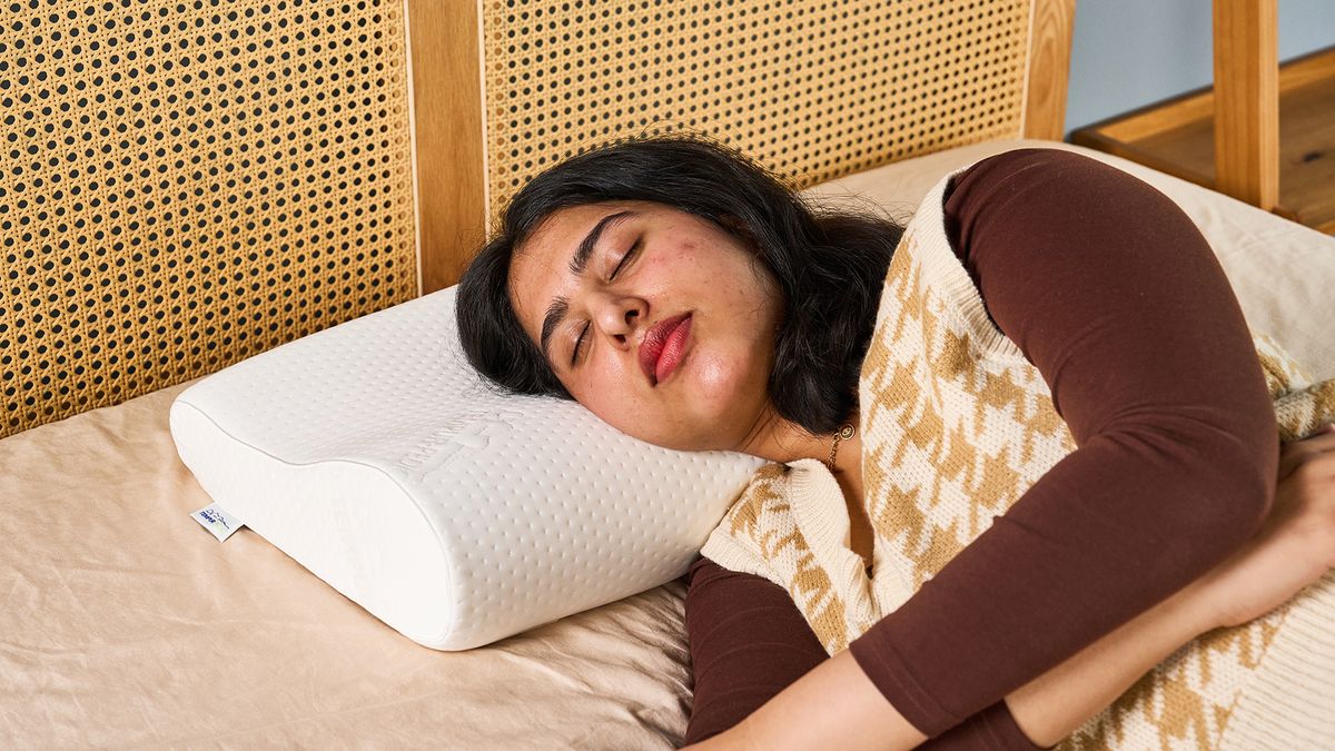 A woman with dark hair uses the Tempur-Pedic Tempur Neck Pillow for side sleeping.