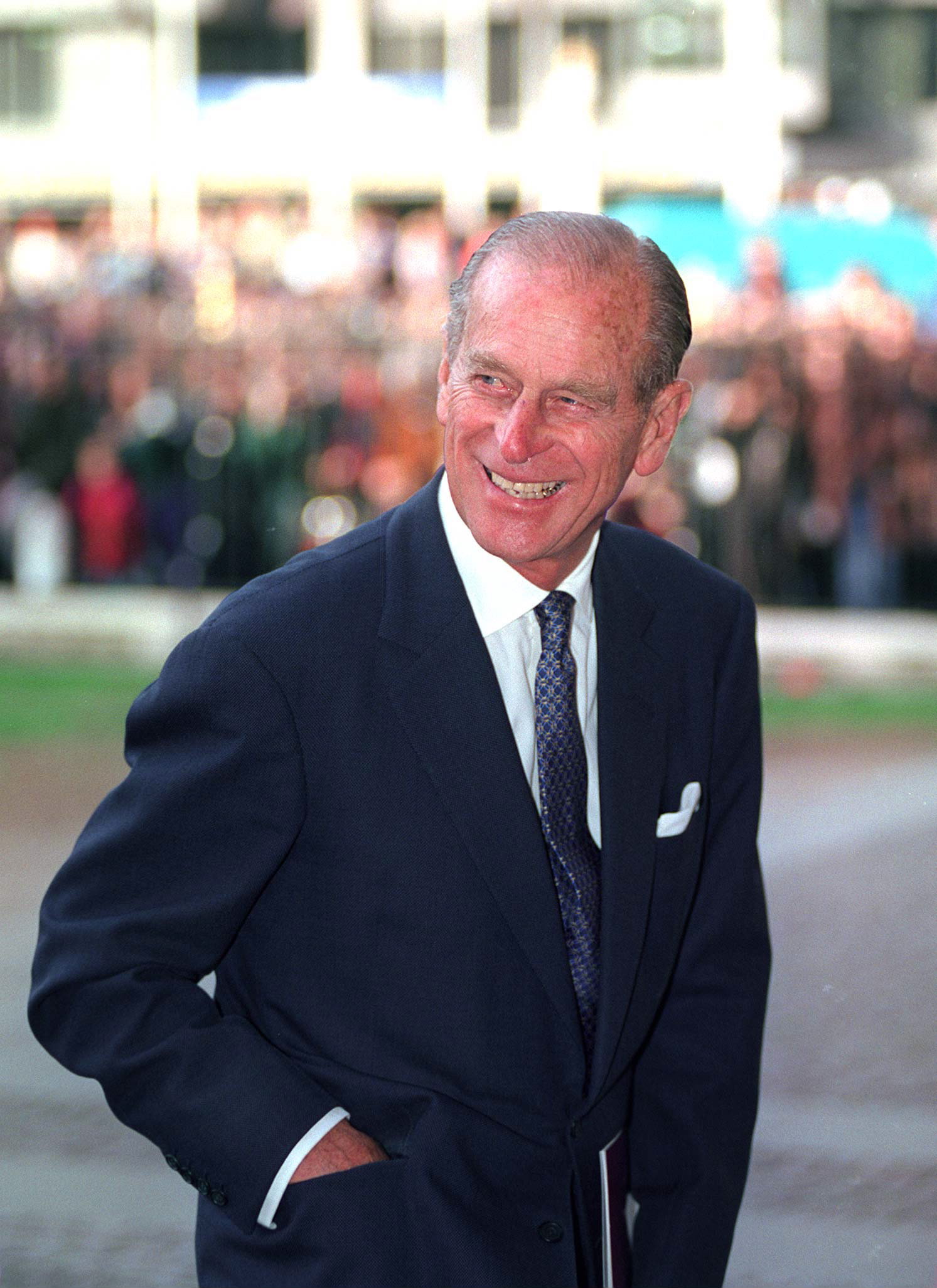 Prince Philip wearing a blue suit and smiling with one hand in his pocket