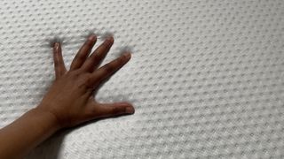 A hand touches the surface of the Emma Original mattress