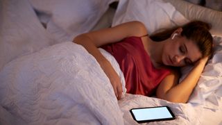 Music for sleep. Female lying in bed listening to music on AirPods