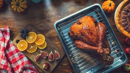 A best turkey roasting pan next to a chopping board with fruits