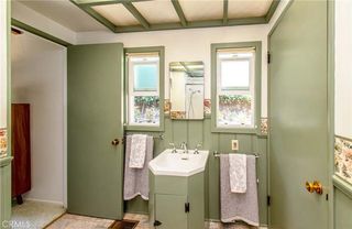 A bathroom painted in sage green with a coffered ceiling, a sink, and two small windows