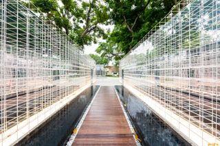 A wooden walkway surrounded by square wire walls.