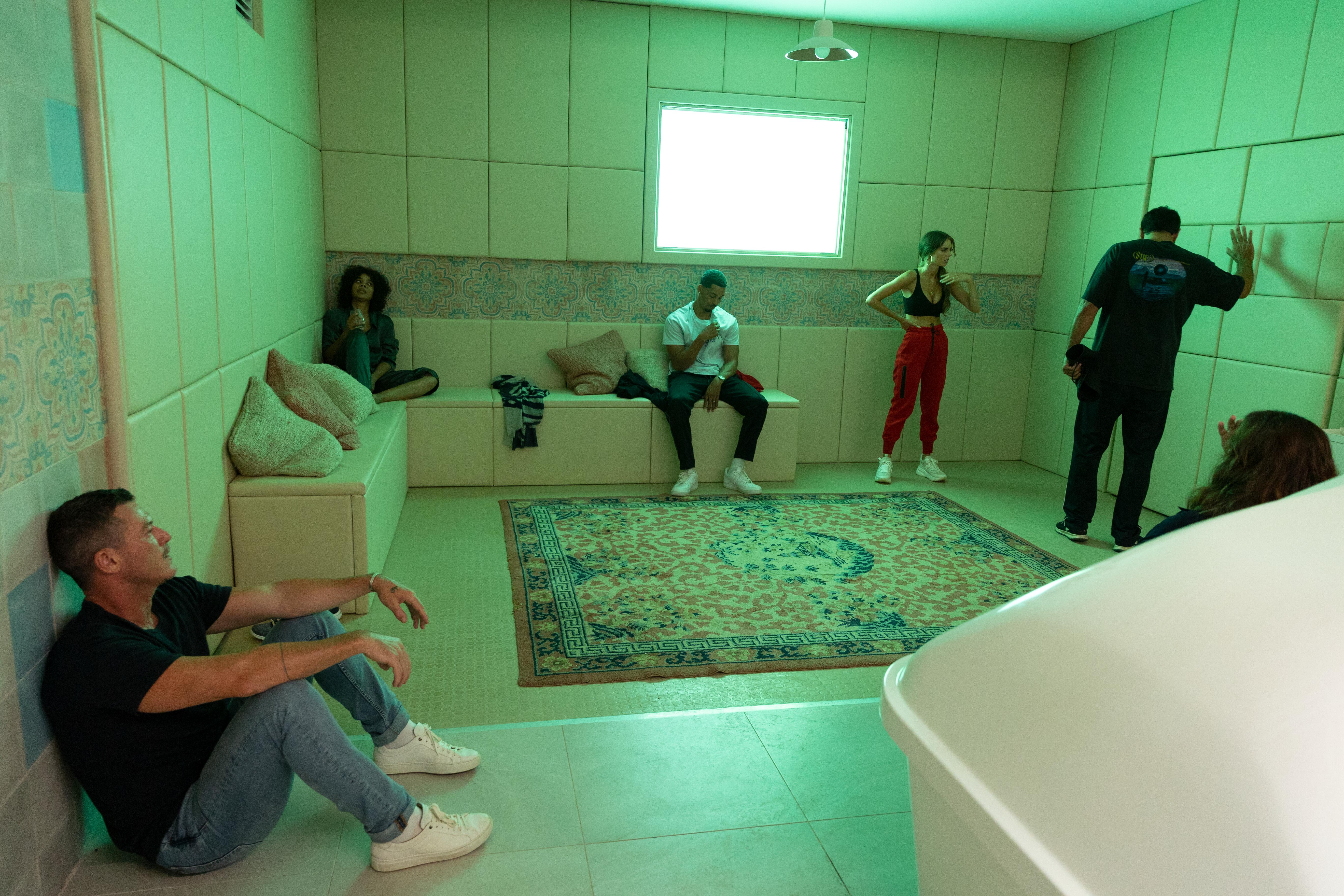 a group of people stand around a green lit room in the nine perfect strangers season 1 finale
