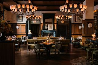 Restaurant interior at Locanda Verde Hudson Yards, with dark wood-lined walls and chandeliers