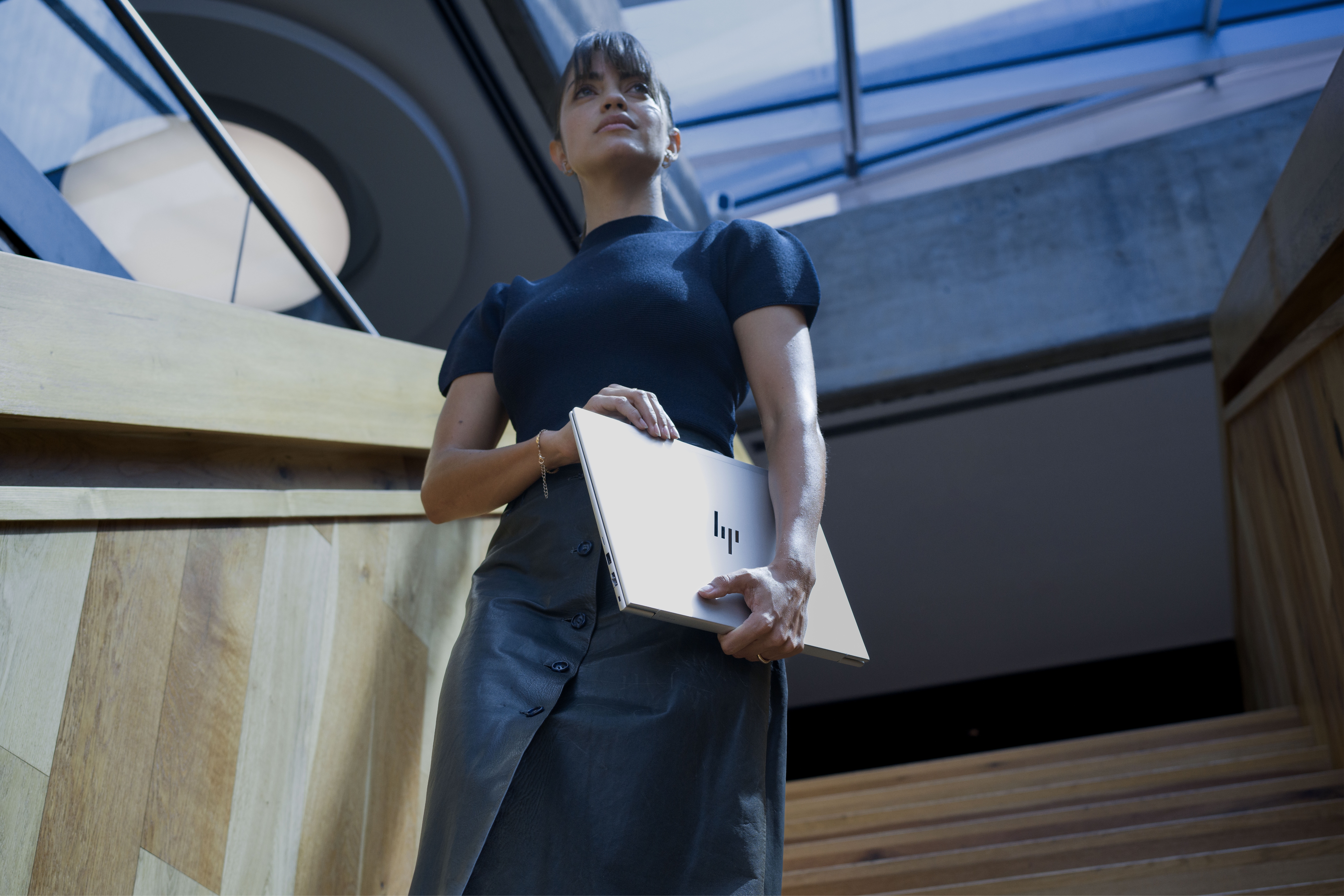Woman walking down stairs holding an HP laptop