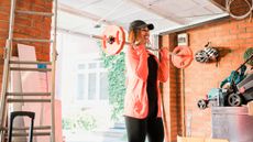 Smiling woman exercising with a barbell in a garage