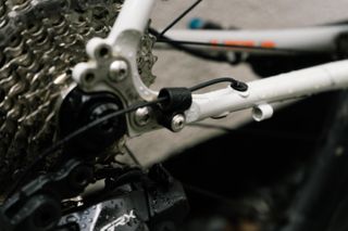 A wire protruding from a white bicycle chainstay