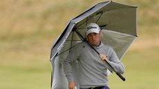 Justin Thomas holds an umbrella into driving rain and strong winds at the 2024 Open Championship at Royal Troon