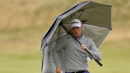 Justin Thomas holds an umbrella into driving rain and strong winds at the 2024 Open Championship at Royal Troon