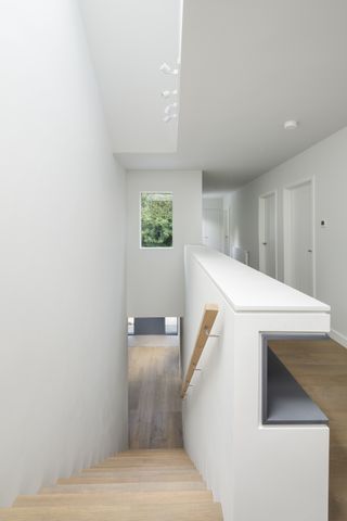 white hallway and staircase with rooflight and window