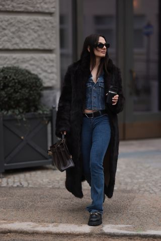 woman wearing a faux fur coat, denim shirt, jeans, and loafers