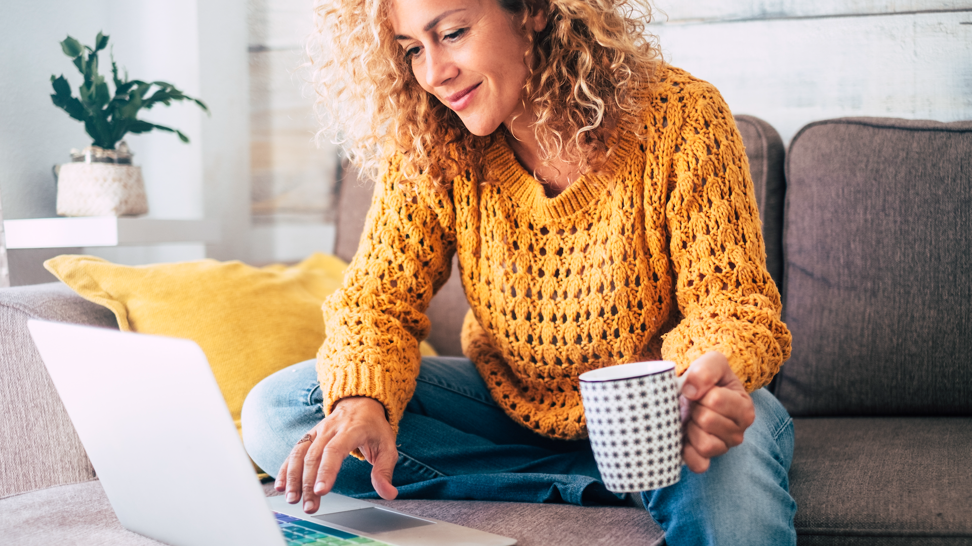 Woman using laptop while sat on sofa