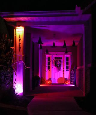 Halloween porch decor with 'floating' witches hats, paper bats, lights and skeleton figurine