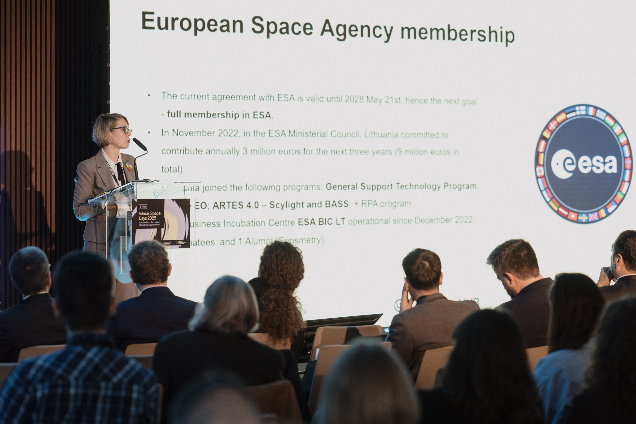 A woman at a podium with a powerpoint in the background that has the ESA logo.