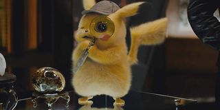 Detective Pikachu looking through a magnifying glass while standing on someone's desk