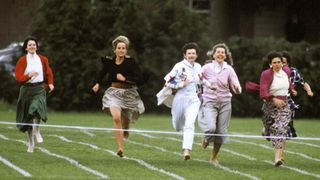 Princess Diana running down a field at a childrens sports day against 5 other mothers, shes wearing a maxi skirt and black blazer