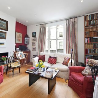 living room with white wall and wooden flooring with sofa and cushions