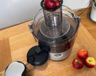 A Nutribullet Pro on wooden dining table with bowls of apples and whole apple in chute
