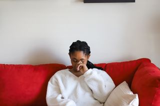 Definition of trauma: A woman looks sad while sitting on a sofa