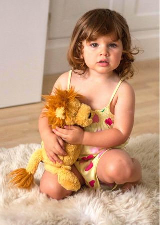 Child sat on floor holding toy lion