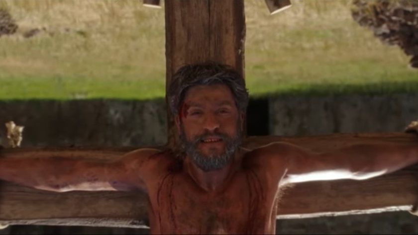 Saint Peter smiling gently while enduring crucifixion upside-down by the Romans, in a screenshot from docuseries &quot;The Saints&quot; season 2.