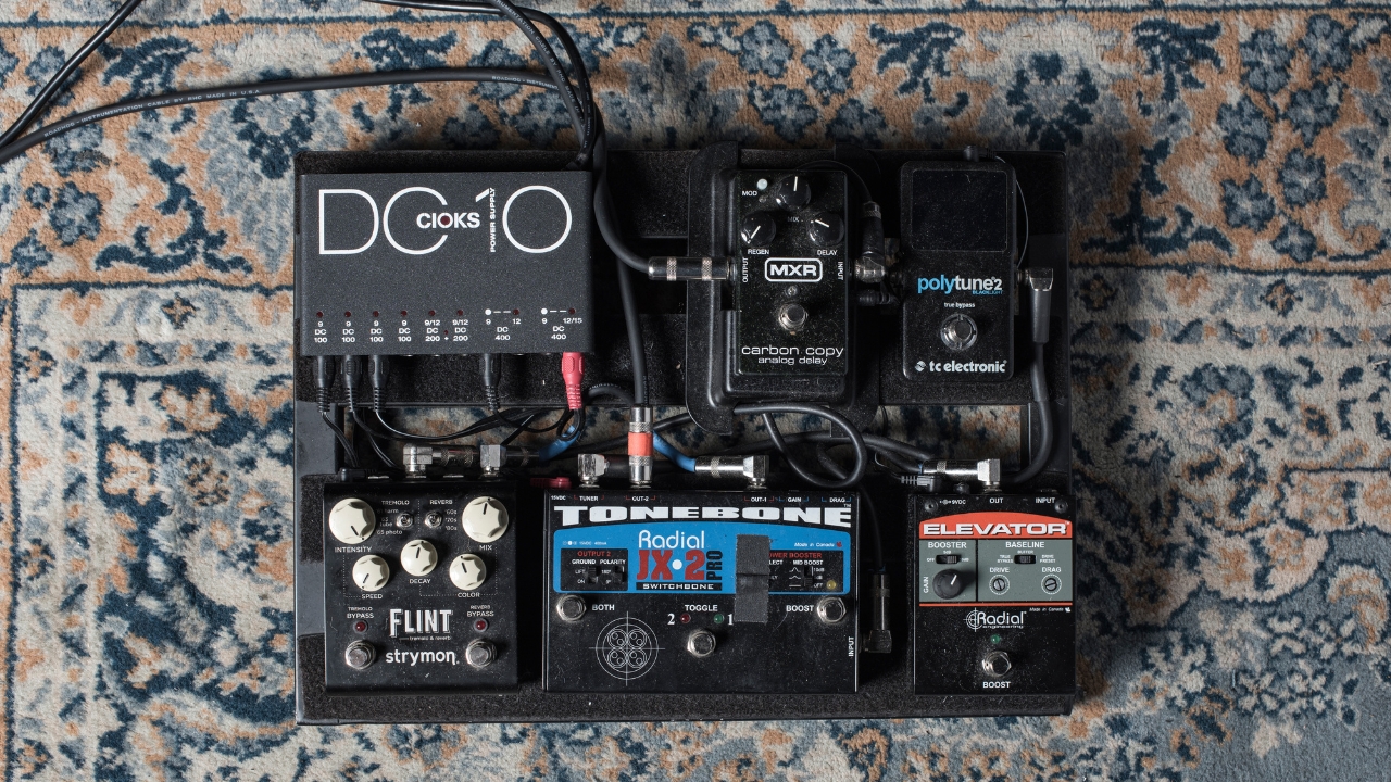 A pedalboard and pedals on a rug with power supply mounted to the top