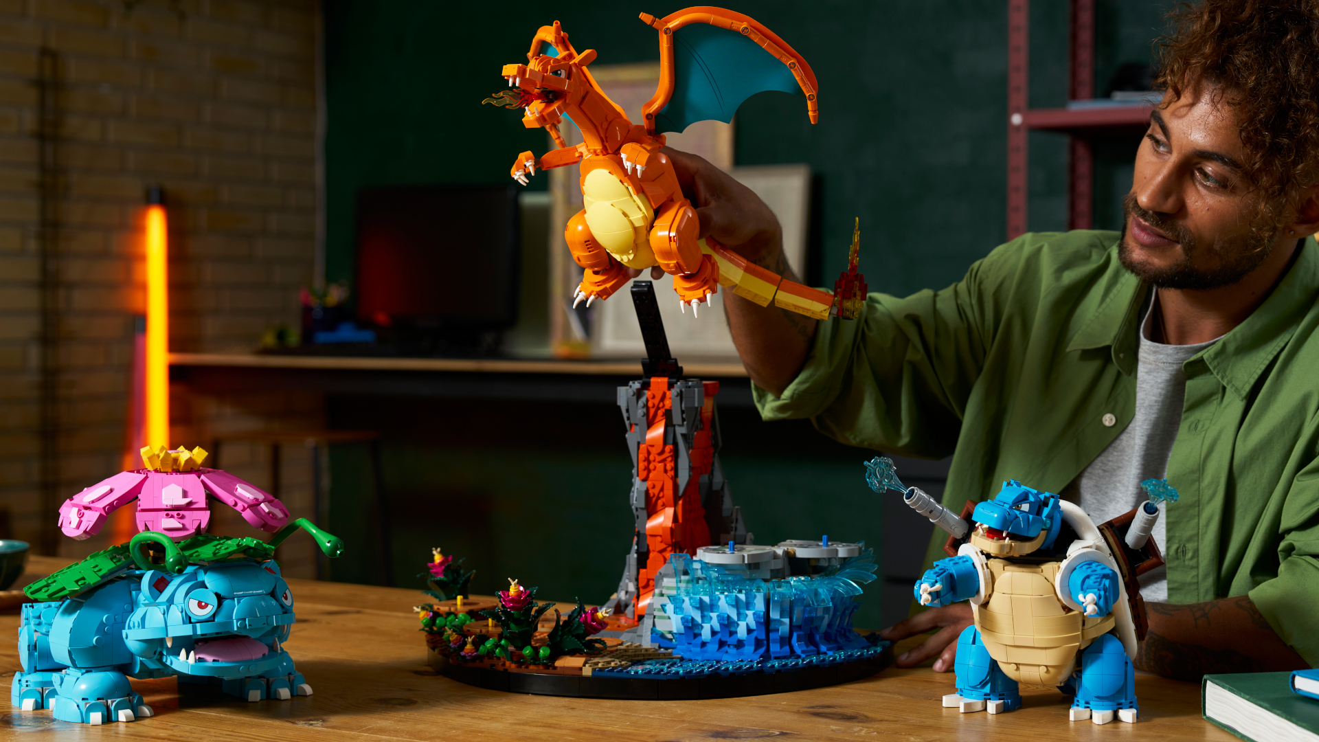 A man poses the Lego Venusaur, Charizard, and Blastoise set