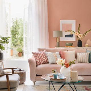living room with pink wall white window with curtain pink sofa with designed cushions