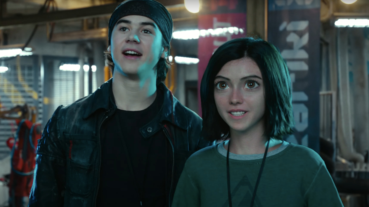 Hugo and Alita stand in the Motorball pits in Alita: Battle Angel.