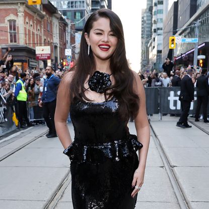 Selena Gomez on the red carpet for Emilia Perez wearing a black sequin gown and a bright red lipstick