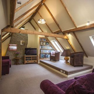 attic room with arm chairs and book shelve and television
