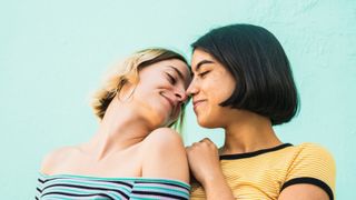Side View Of Smiling Lesbian Couple Romancing Against Wall - stock photo