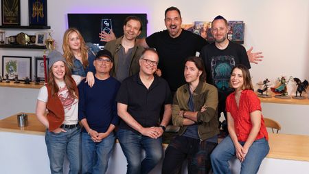 The Critical Role cast with Chris Perkins and Jeremy Crawford, in front of shelves filled with Critical Role paraphernalia