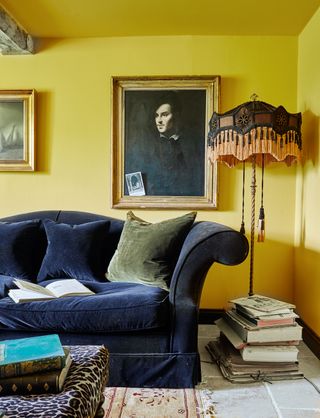 living room with yellow walls black sofa and framed portrait and old standard lamp