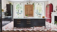 A kitchen with a large island, black cabinets, and tiled flooring that means wooden floorboards in a cut-out design
