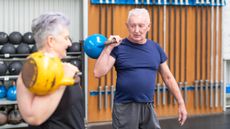 Senior man and woman in a gym holding kettlebells