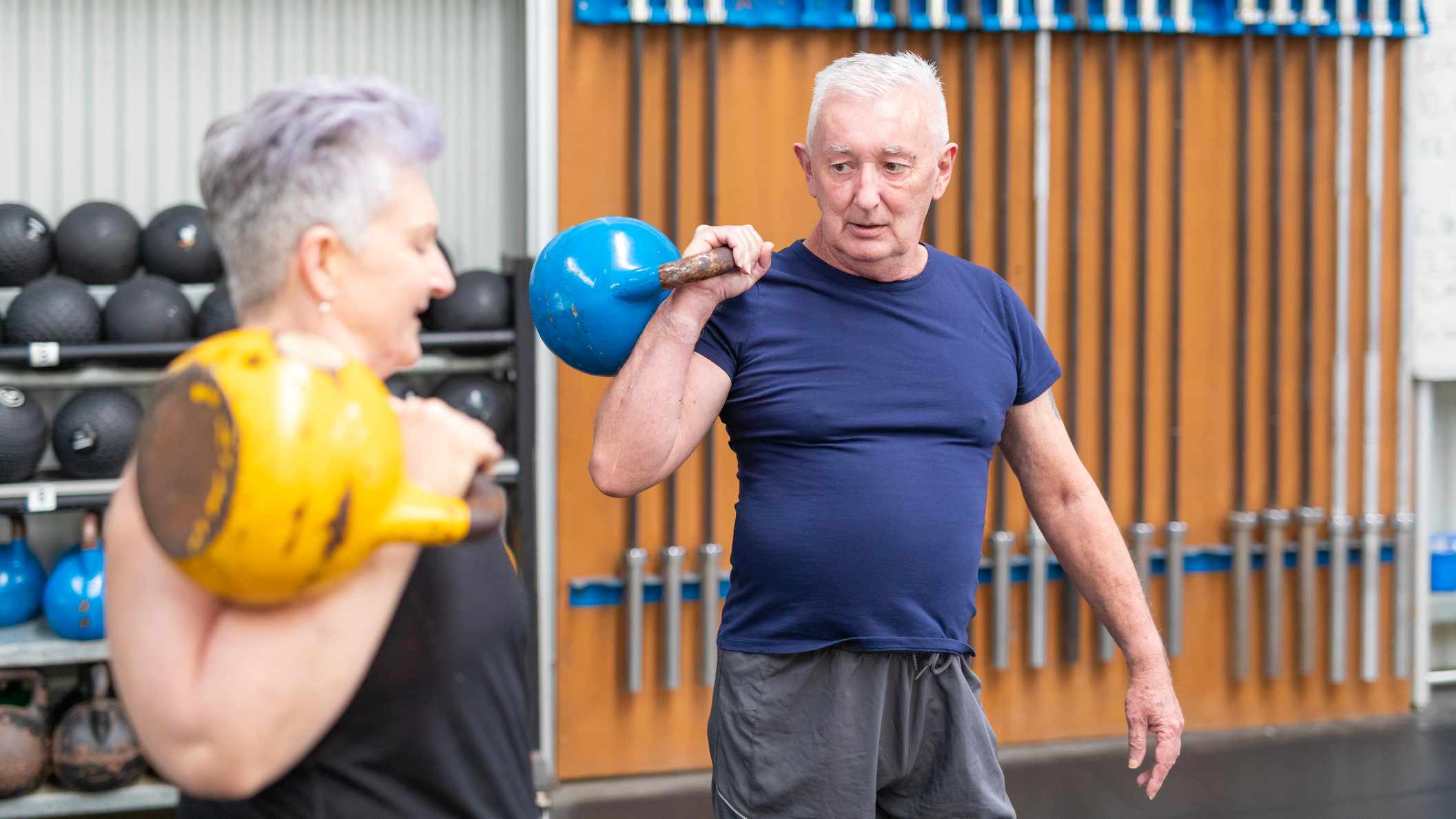 Senior man and woman in a gym holding kettlebells