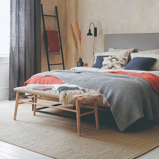 A bedroom with limewash-effect walls and a large jute area rug under the bed