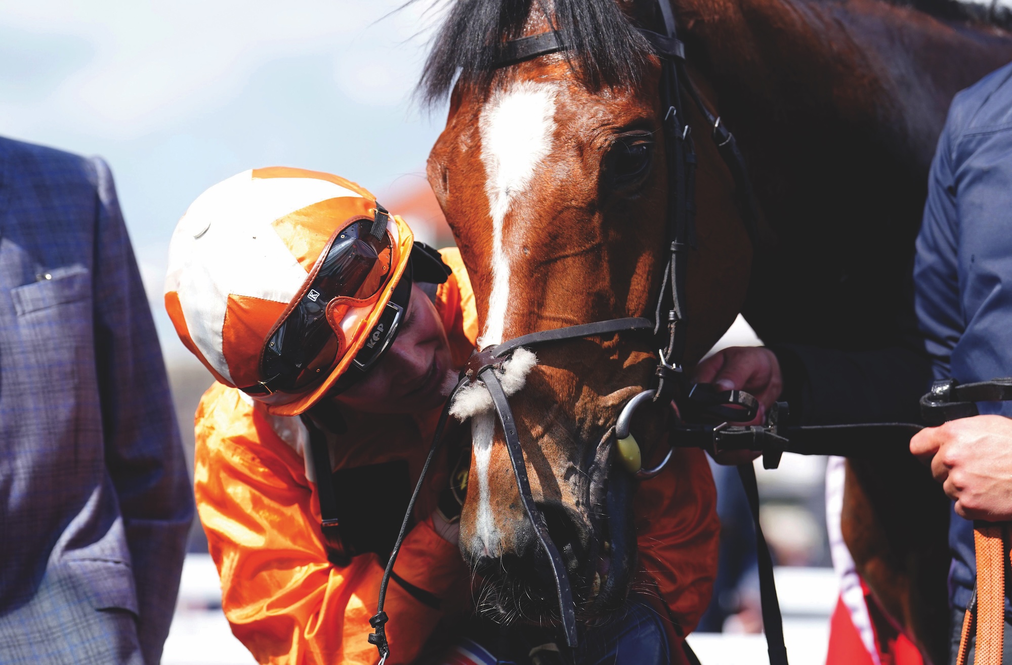 Saffie Osborne in orange silks kisses racehorse