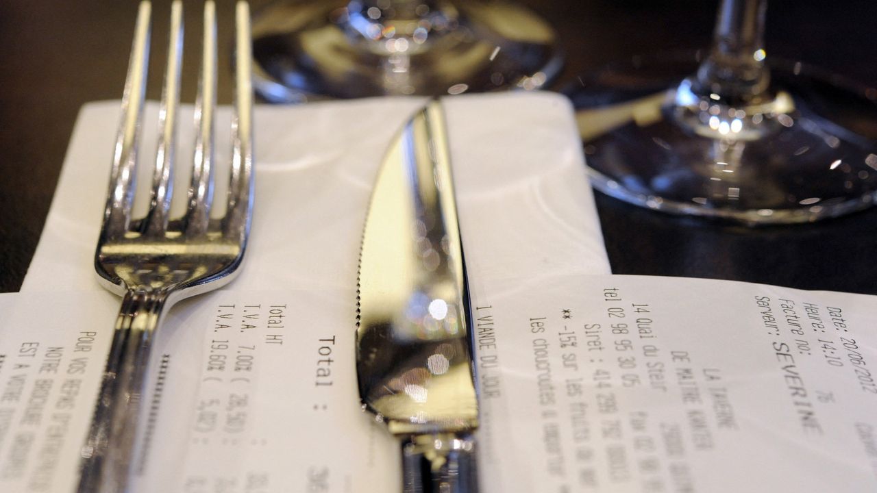 A picture of a restaurant table with a knife and fork sitting on top of the bill