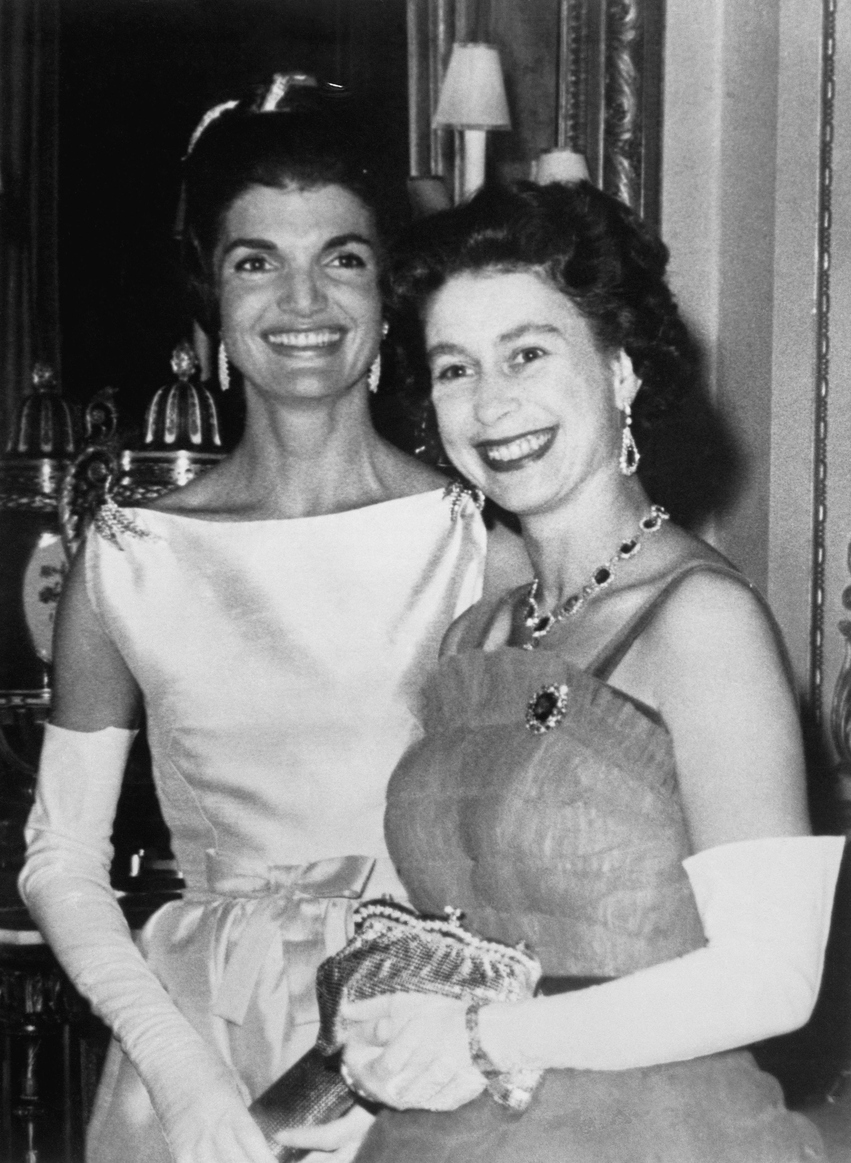 Jackie Kennedy and Queen Elizabeth standing next to each other wearing evening gowns