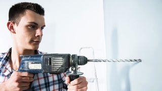 Man drilling a blue wall